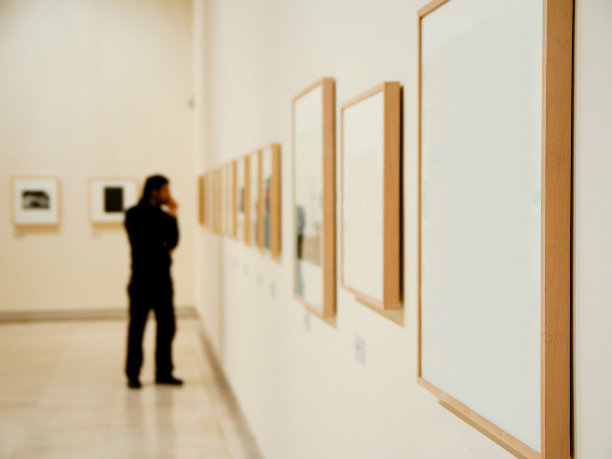 Person observing paintings in art gallery.